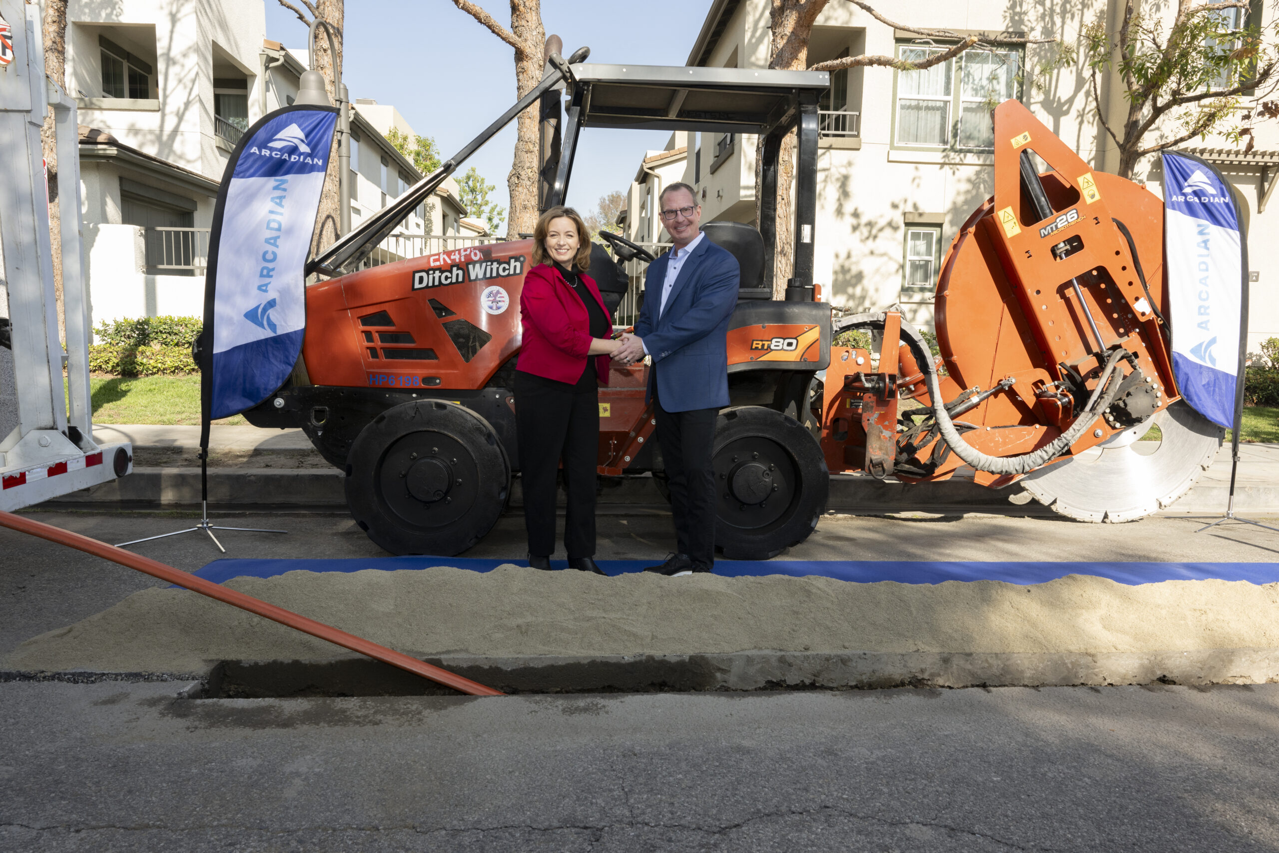 Two individuals standing beside a construction machine, engaged in a conversation.