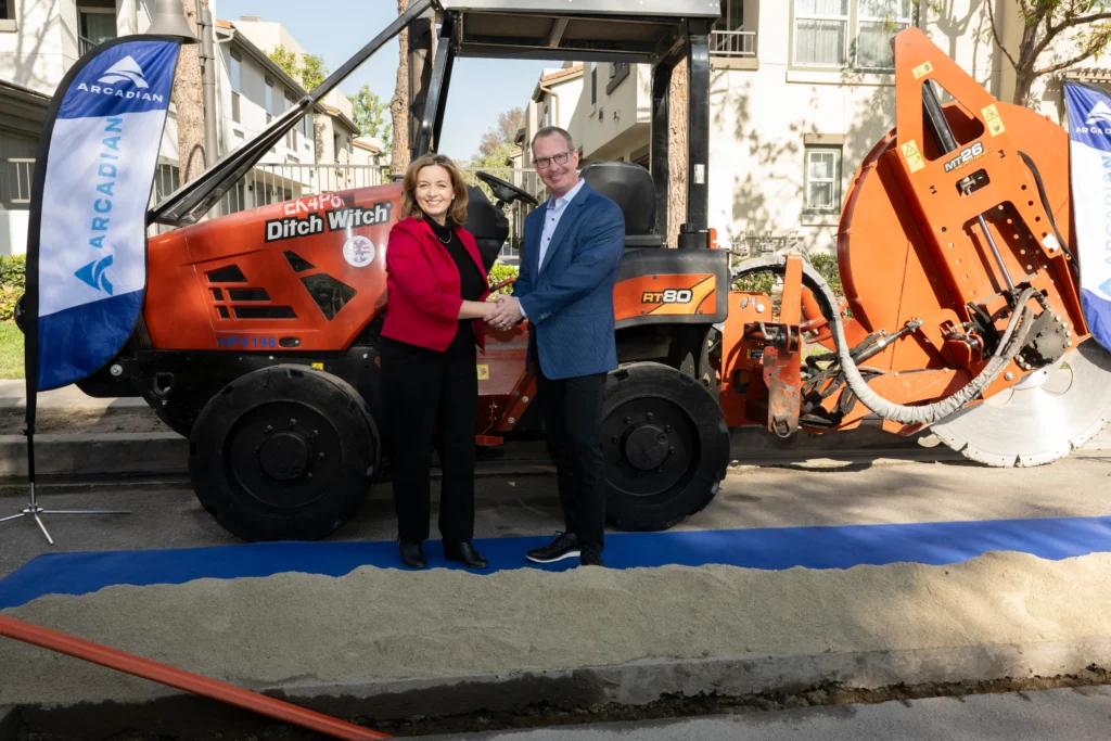 Two individuals standing beside a construction machine, engaged in a conversation.